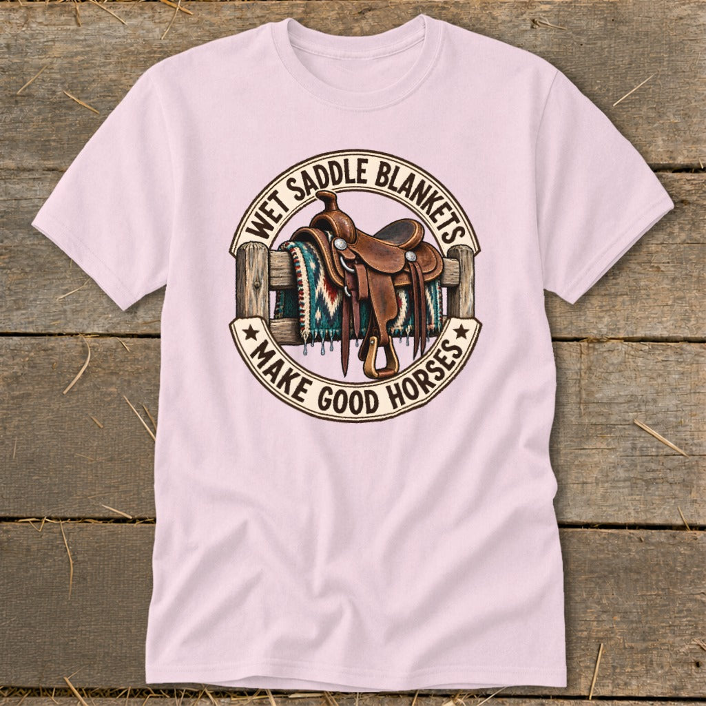 Pink t-shirt with a graphic of a saddle and blanket on a fence, saying "Wet Saddle Blankets Make Good Horses".