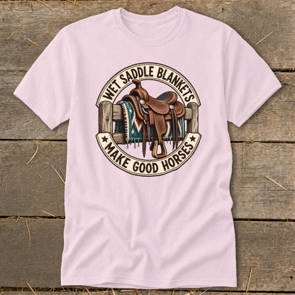 Pink t-shirt with a graphic of a saddle and blanket on a fence, saying "Wet Saddle Blankets Make Good Horses".
