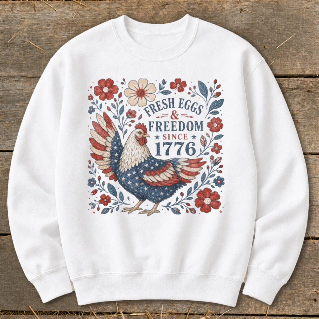 White sweatshirt with patriotic chicken and text "Fresh Eggs & Freedom Since 1776".