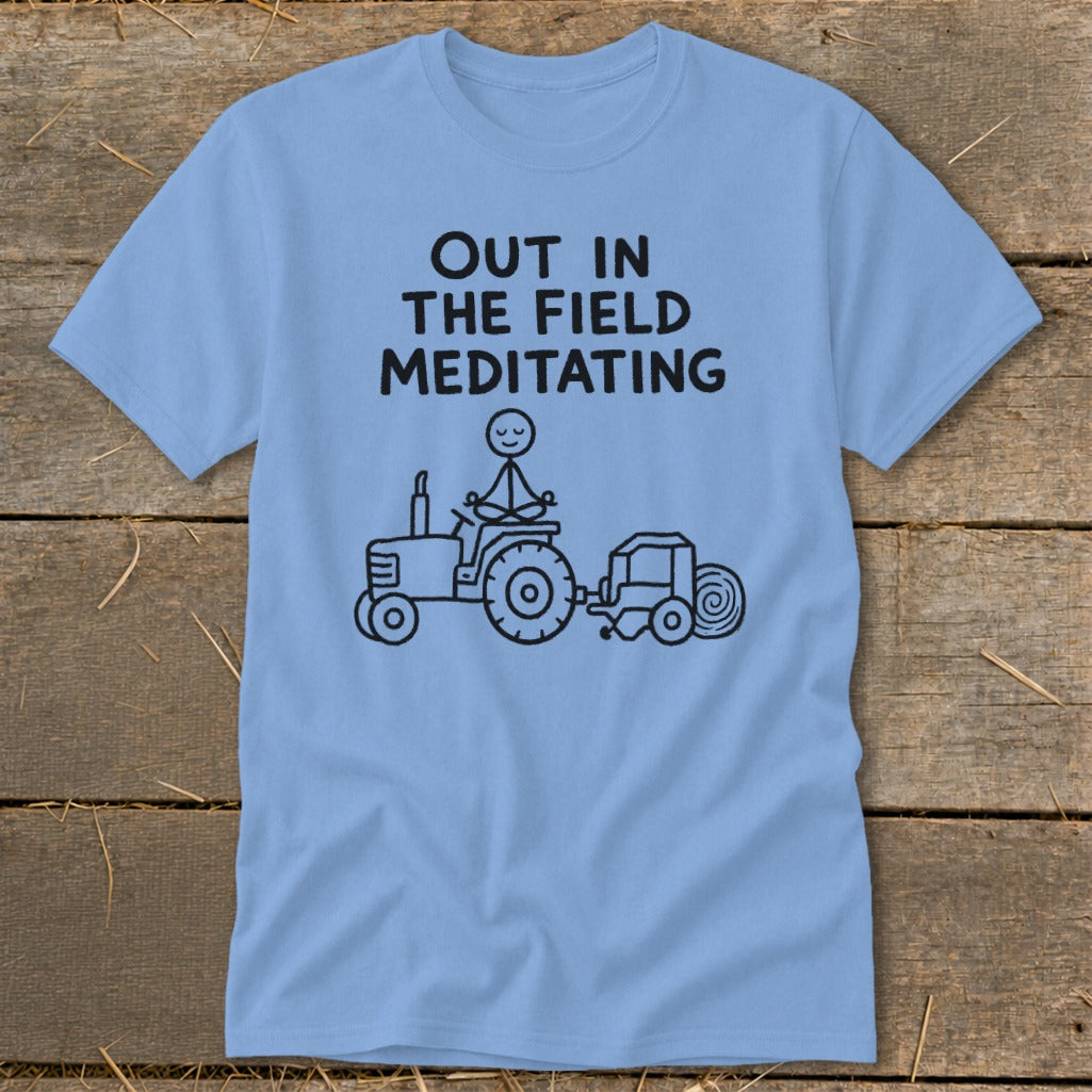 Light blue t-shirt with black text "OUT IN THE FIELD MEDITATING" and a drawing.