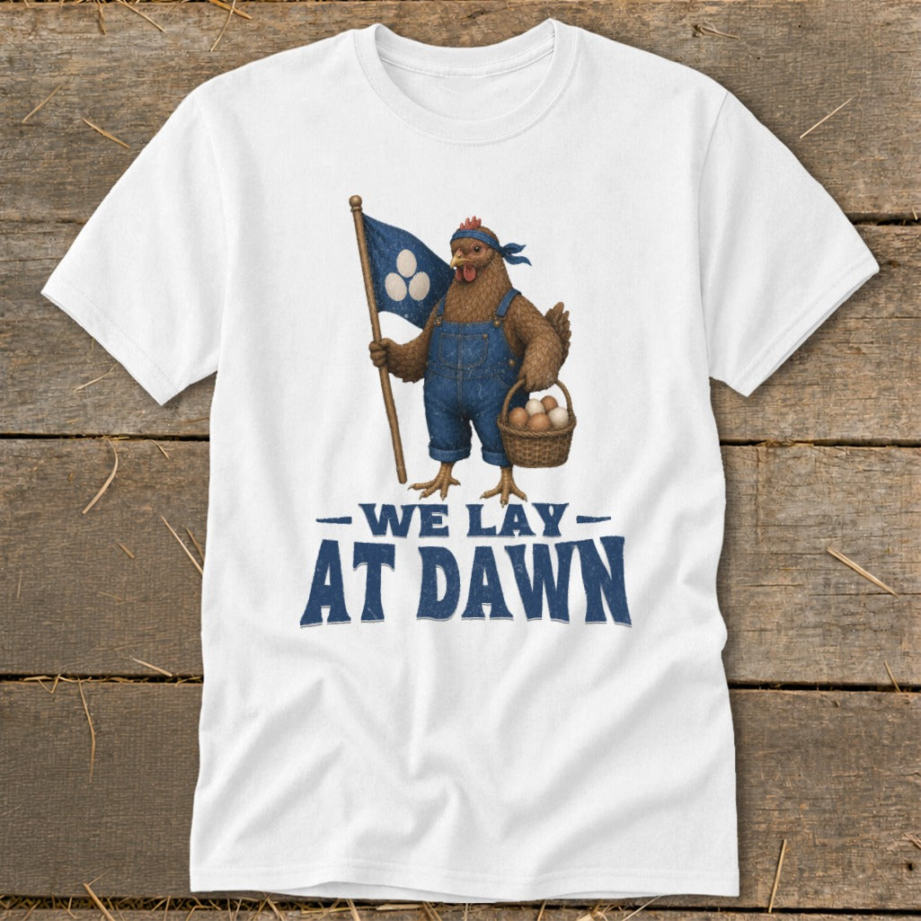 White t-shirt with chicken in overalls holding flag and egg basket, text "WE LAY AT DAWN".