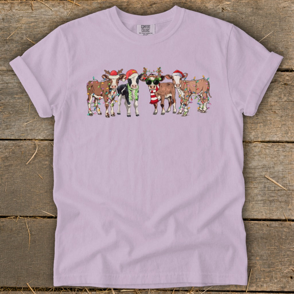 Five cartoon cows wearing Santa hats and Christmas lights.