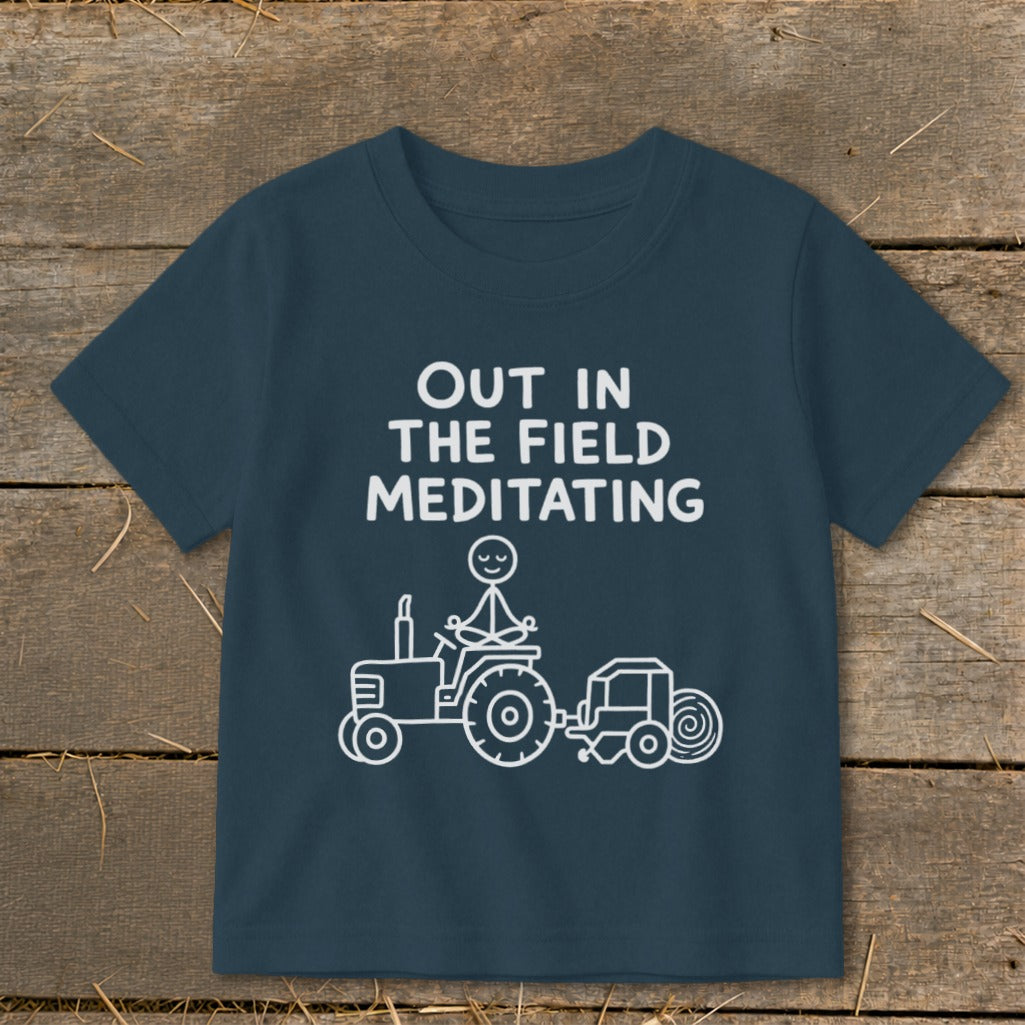 Dark blue shirt with white text and a line drawing of a stick figure meditating on a tractor.
