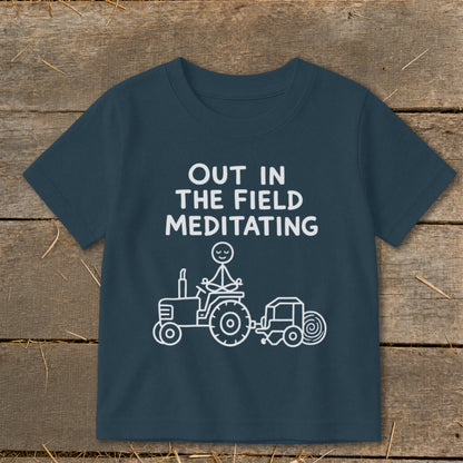 Dark blue shirt with white text and a line drawing of a stick figure meditating on a tractor.