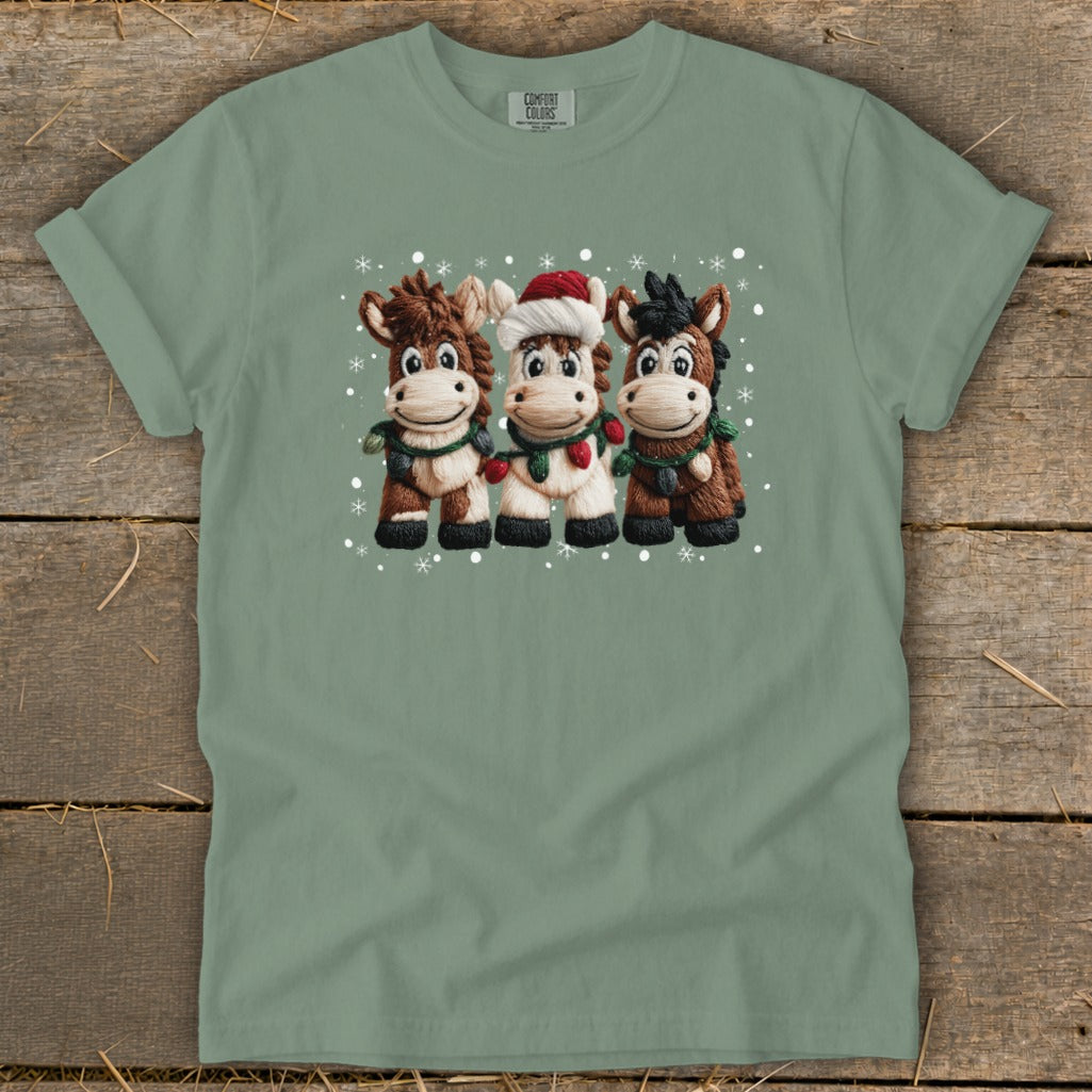 Three cartoon donkeys wearing scarves and Christmas lights, one with a Santa hat.