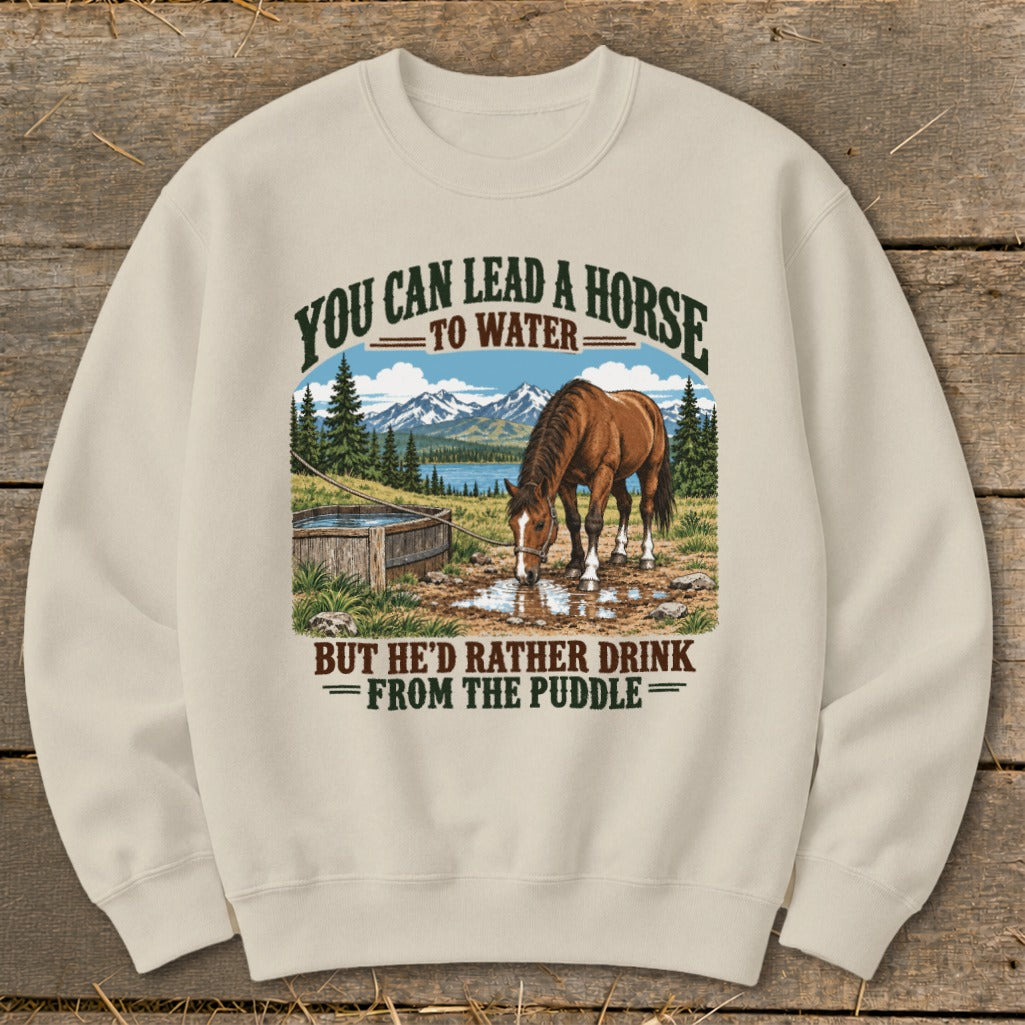 Beige crewneck sweatshirt featuring a graphic of a horse drinking from a puddle with mountain text.