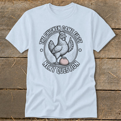 Light blue t-shirt with a chicken and egg graphic and text: "The Chicken Came First, Next Question".