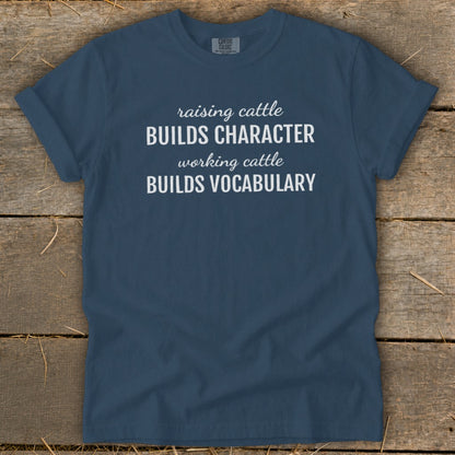Navy blue t-shirt with white text "Raising cattle BUILDS CHARACTER working cattle BUILDS VOCABULARY".