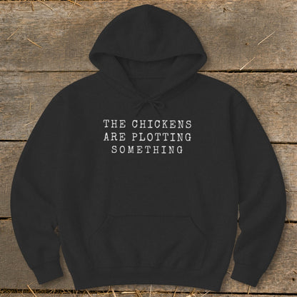 Black hoodie with white text that reads "THE CHICKENS ARE PLOTTING SOMETHING".
