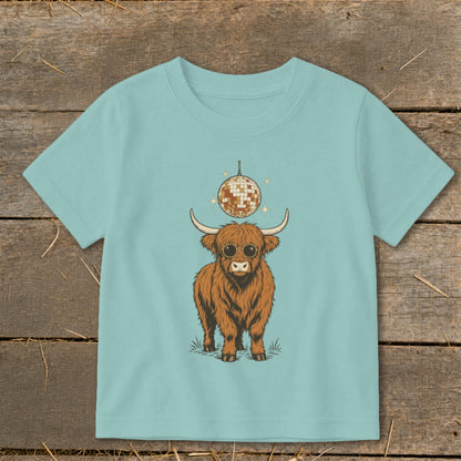 Highland cow with sunglasses and disco ball graphic on a light blue t-shirt.