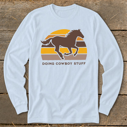 Light blue long sleeve shirt with a brown horse and sunset graphic and text.
