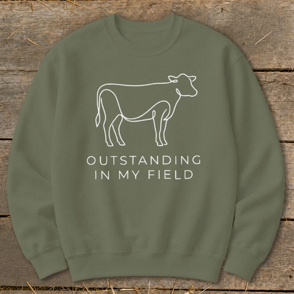 Olive sweatshirt with white line drawing of a cow and text "OUTSTANDING IN MY FIELD".