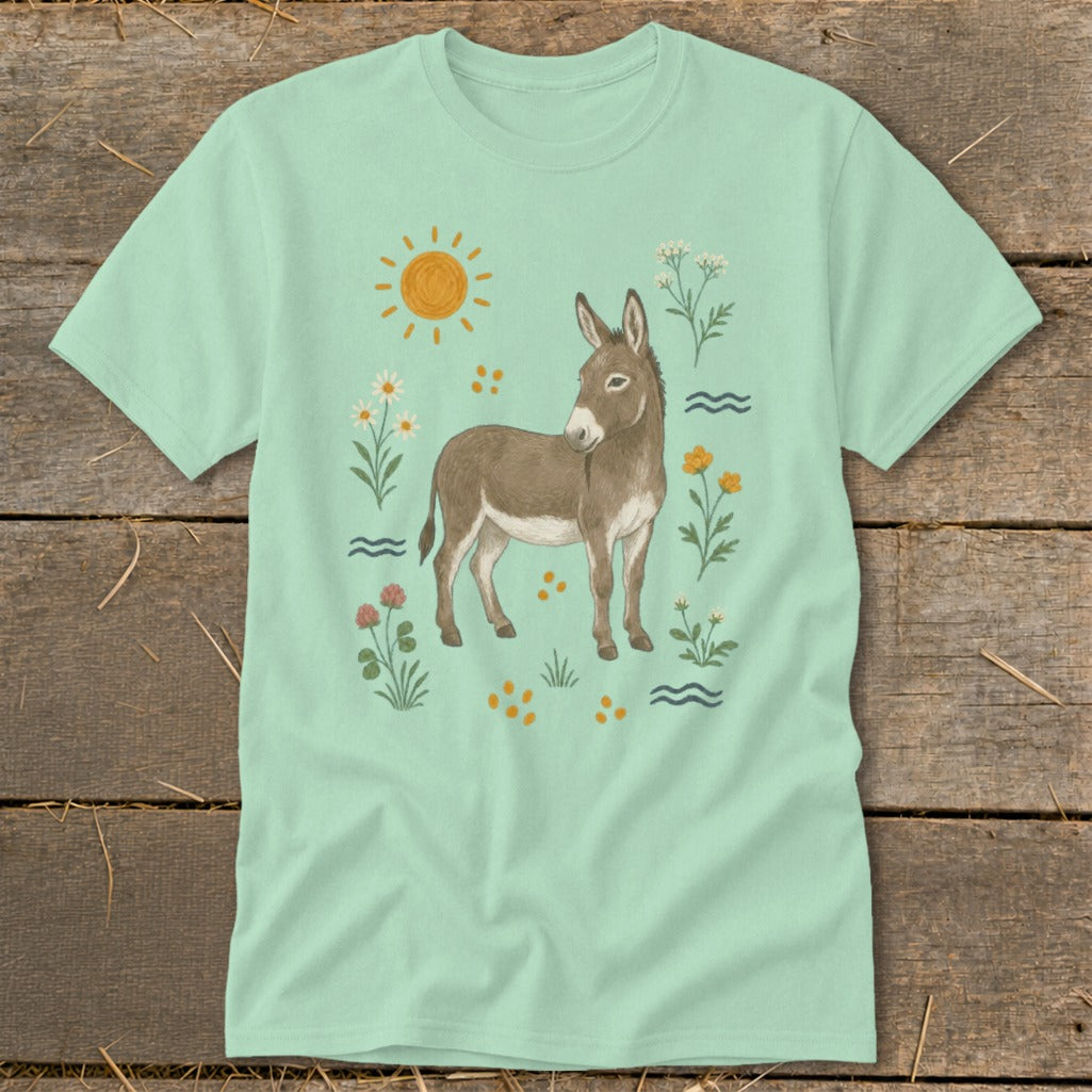 Light green t-shirt with a donkey illustration surrounded by sun, flowers, and waves.