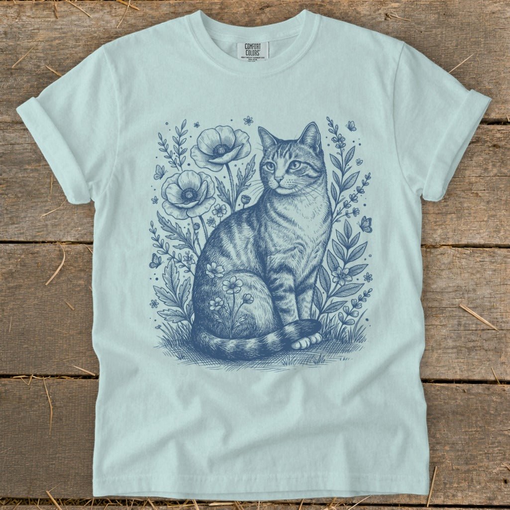Light blue t-shirt with a detailed blue line drawing of a tabby cat among flowers and butterflies.
