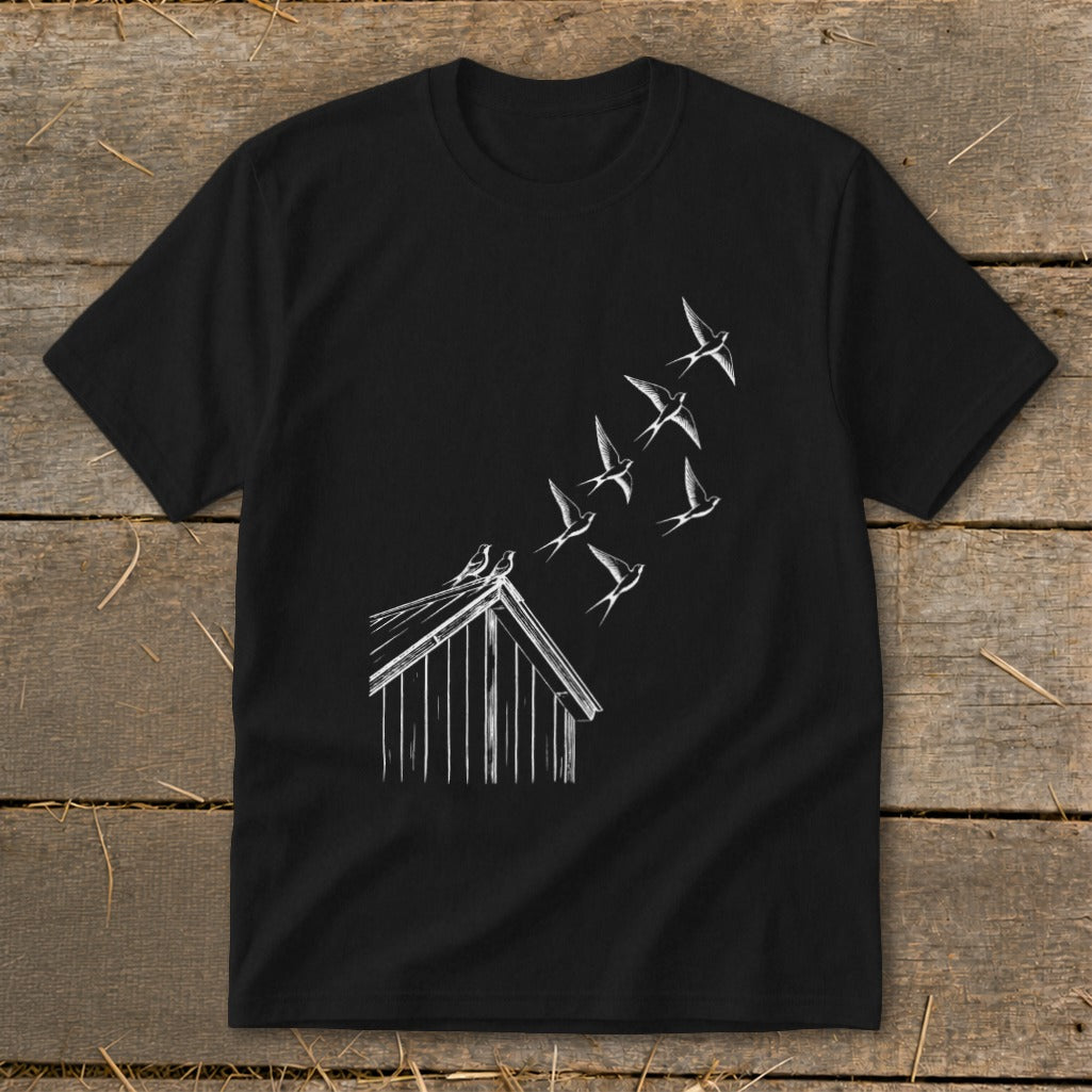 A black short-sleeved t-shirt featuring a white line graphic of birds flying from a cabin roof.