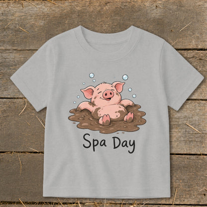 Cartoon pig enjoying a mud bath with "Spa Day" text on a gray t-shirt.