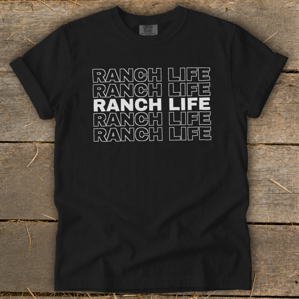 Black t-shirt featuring the text Ranch Life repeated in stacked, outlined white letters on a wooden background.