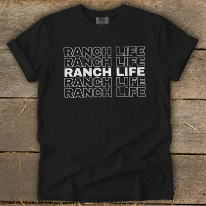 Black t-shirt featuring the text Ranch Life repeated in stacked, outlined white letters on a wooden background.