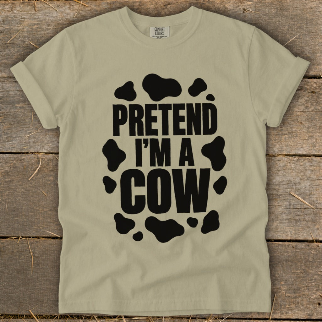 Tan t-shirt with black "PRETEND I'M A COW" text and cow spots.