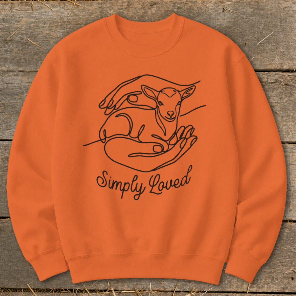 Orange crewneck sweatshirt with line art of hands holding a lamb and the text "Simply Loved".