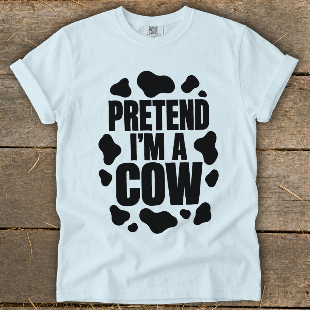 White t-shirt with black "PRETEND I'M A COW" text and cow spots.