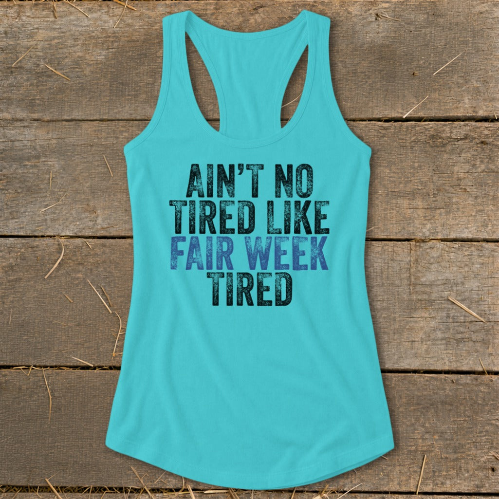 Teal tank top with black and blue text: "AIN'T NO TIRED LIKE FAIR WEEK TIRED."
