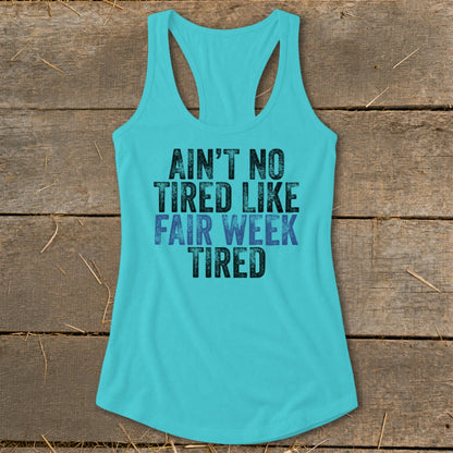 Teal tank top with black and blue text: "AIN'T NO TIRED LIKE FAIR WEEK TIRED."