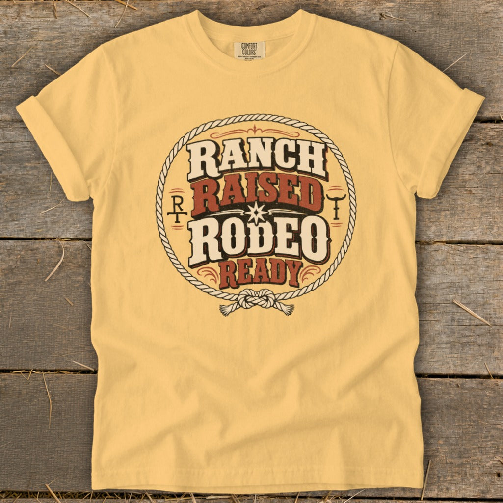 A yellow short-sleeve t-shirt with a vintage rodeo graphic design printed centrally on a wooden background.