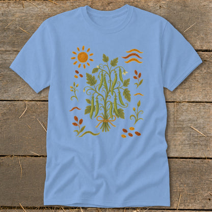 Light blue t-shirt with embroidered pea plant, sun, and abstract elements.