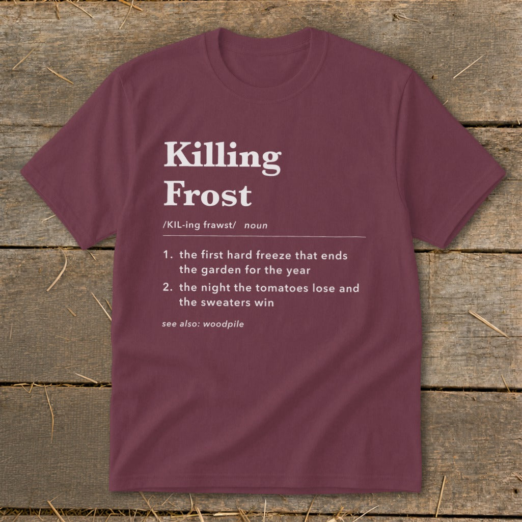 A maroon crewneck t-shirt featuring dictionary-style text defining Killing Frost displayed against a rustic wooden background.