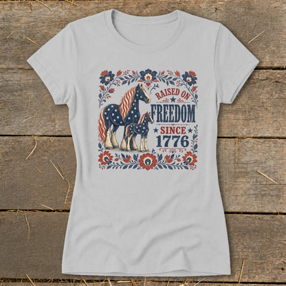T-shirt with horses and "Raised on Freedom Since 1776" text in patriotic colors.