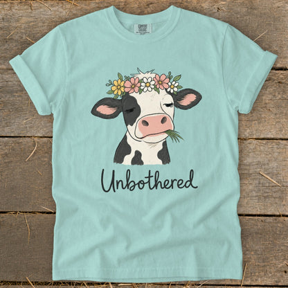 Cow with flower crown eating grass, text "Unbothered".