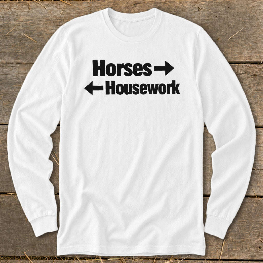 A white long-sleeved t-shirt features black text that reads Horses with a right-pointing arrow above Housework with a left-pointing arrow.