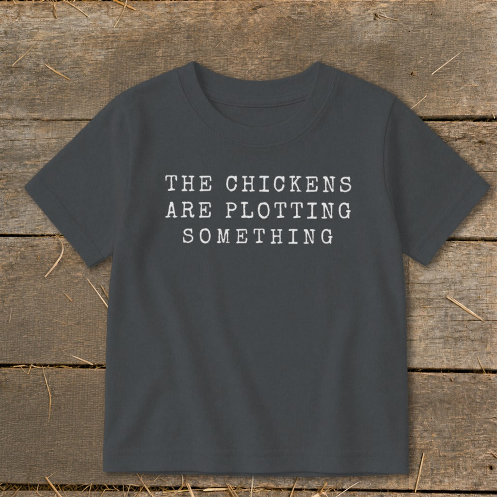 Dark gray t-shirt with white text "THE CHICKENS ARE PLOTTING SOMETHING"