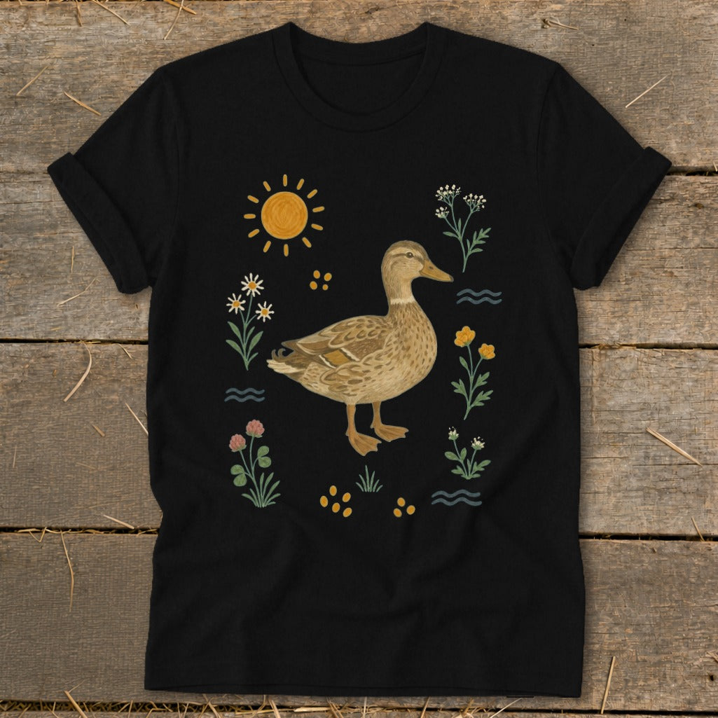 Black t-shirt with a duck illustration surrounded by flowers, sun, and water.