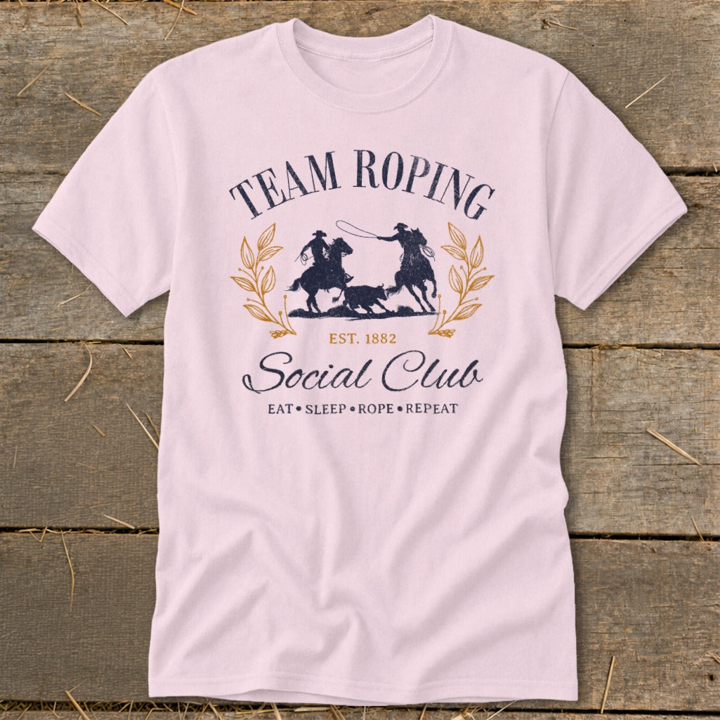 Pink t-shirt with "Team Roping Social Club" graphic and rodeo scene.