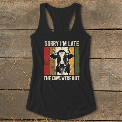 Black tank top with a cow graphic and text "SORRY I'M LATE THE COWS WERE OUT".