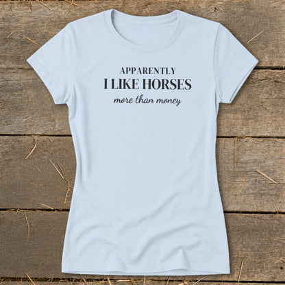 Light blue t-shirt with black text: "APPARENTLY I LIKE HORSES more than money".