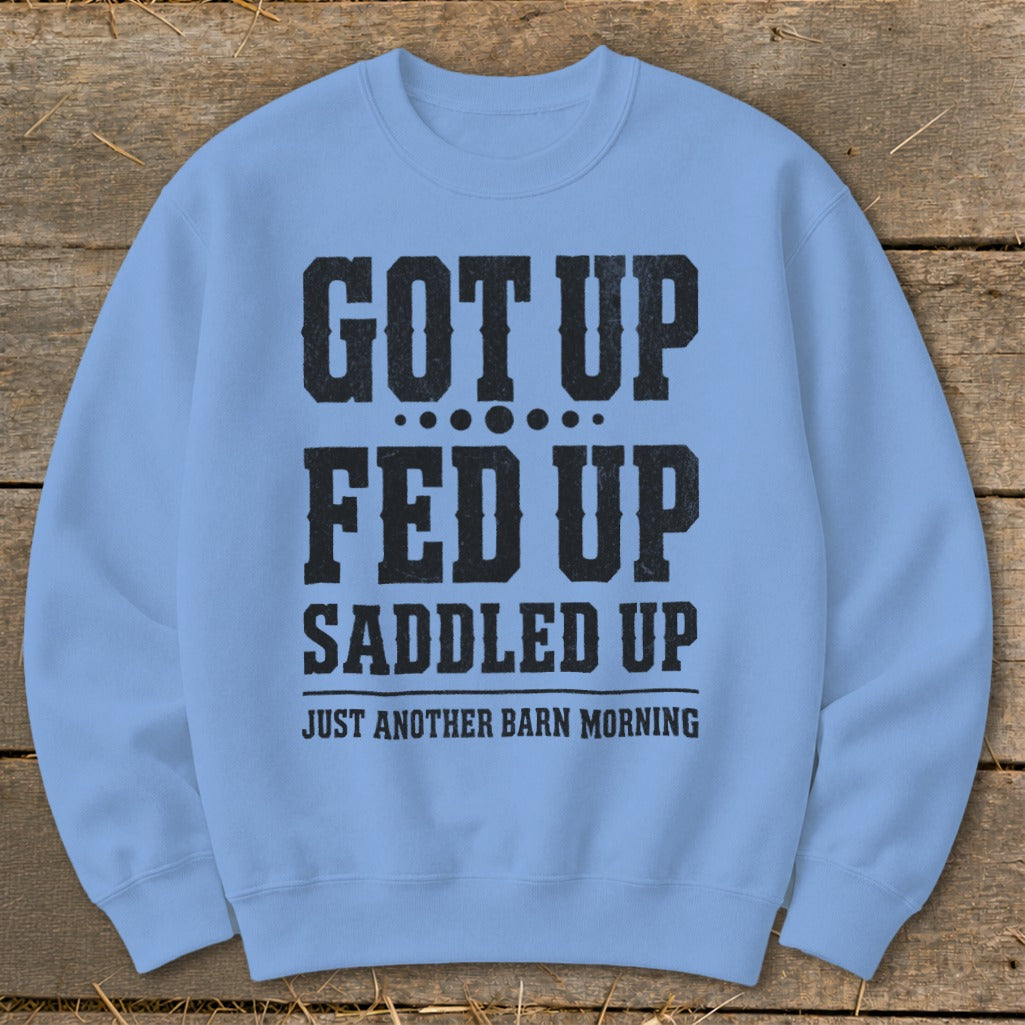 Light blue crewneck sweatshirt with black text: "GOT UP FED UP SADDLED UP JUST ANOTHER BARN MORNING".