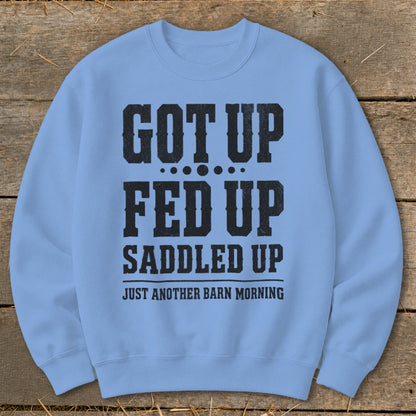 Light blue crewneck sweatshirt with black text: "GOT UP FED UP SADDLED UP JUST ANOTHER BARN MORNING".