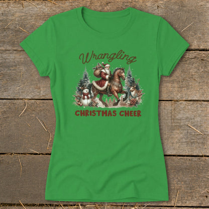 Green t-shirt with Santa riding a horse, text "Wrangling Christmas Cheer", snowman, and deer.