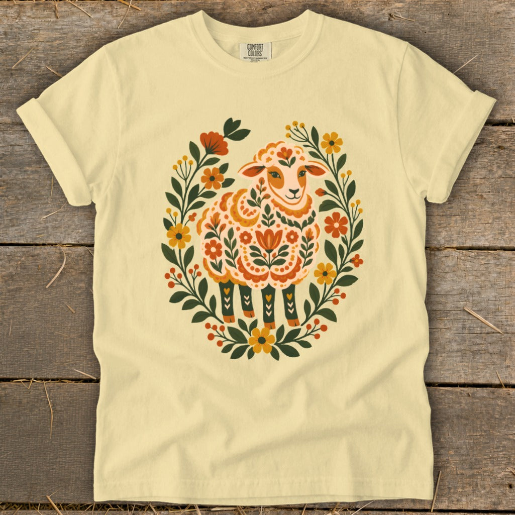 Light yellow t-shirt with a folk art style sheep in a floral wreath.