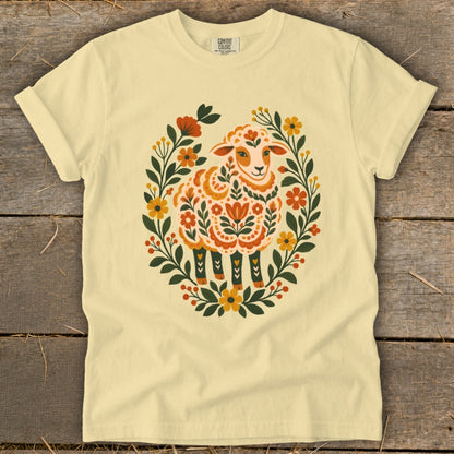 Light yellow t-shirt with a folk art style sheep in a floral wreath.