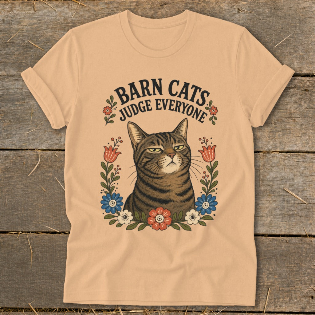 Tabby cat with stern expression surrounded by flowers, text reads "Barn Cats Judge Everyone."