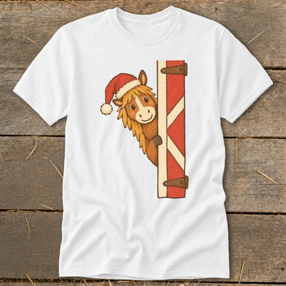 White t-shirt with a cartoon horse wearing a Santa hat peeking from a red barn door.
