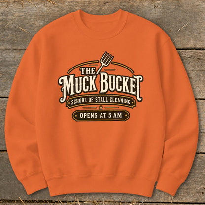 Orange sweatshirt with "The Muck Bucket School of Stall Cleaning Opens at 5 AM" logo.