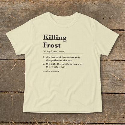 A cream-colored t-shirt with black text featuring a humorous definition of Killing Frost laid flat on wooden planks.