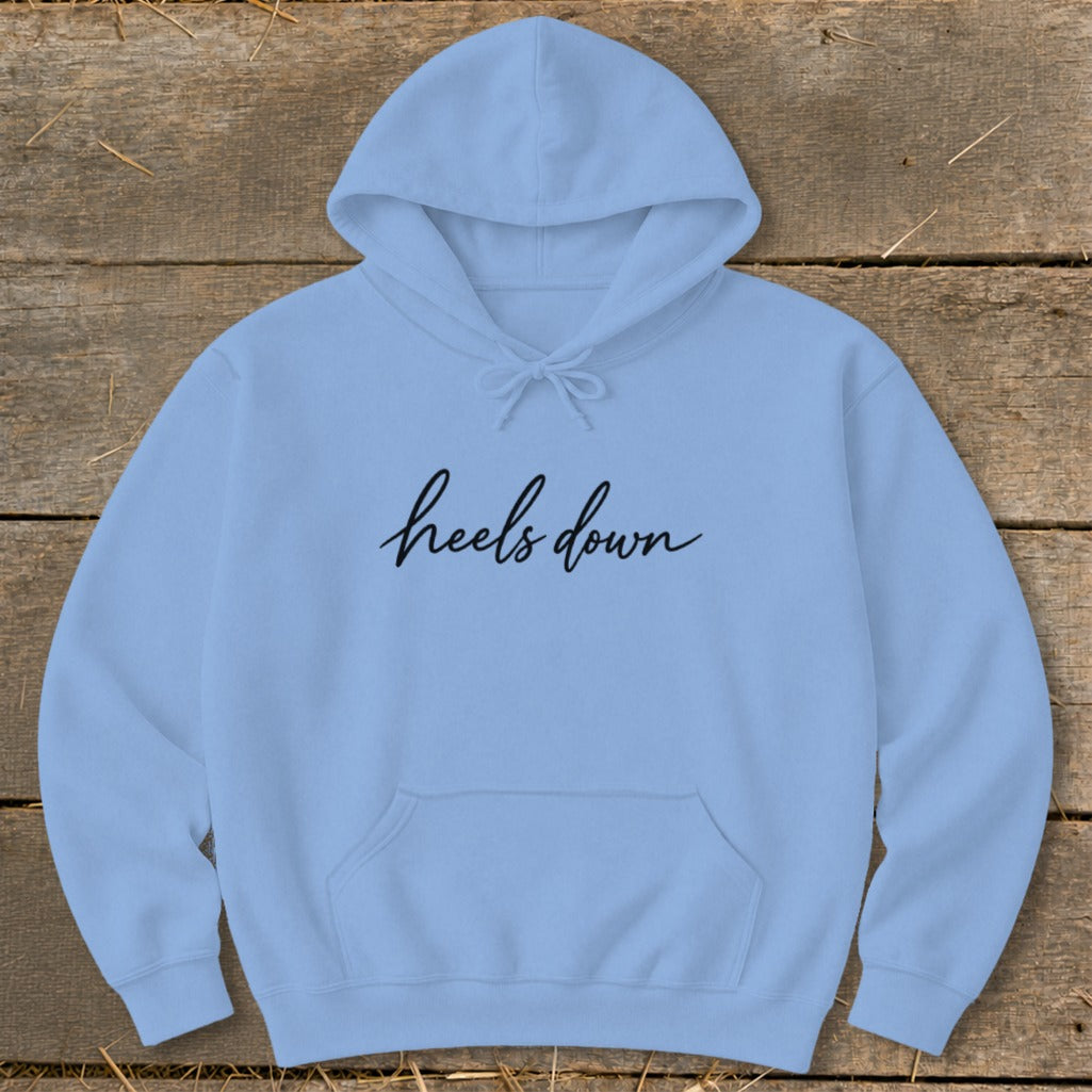 Light blue hoodie with "heels down" in black cursive text, laid flat.