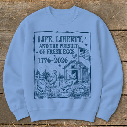 Life, Liberty, and the Pursuit of Fresh Eggs 1776-2026 graphic on light blue sweatshirt.