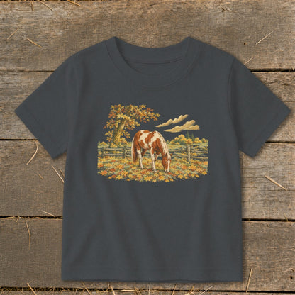 Brown and white horse grazing in a field of autumn leaves.